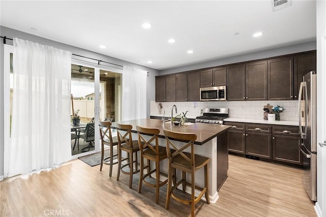 24521 Snapdragon Way, Lake Elsinore, CA 92532 - kitchen featuring appliances with stainless steel finishes, dark brown cabinetry, tasteful backsplash, a kitchen bar, and recessed lighting