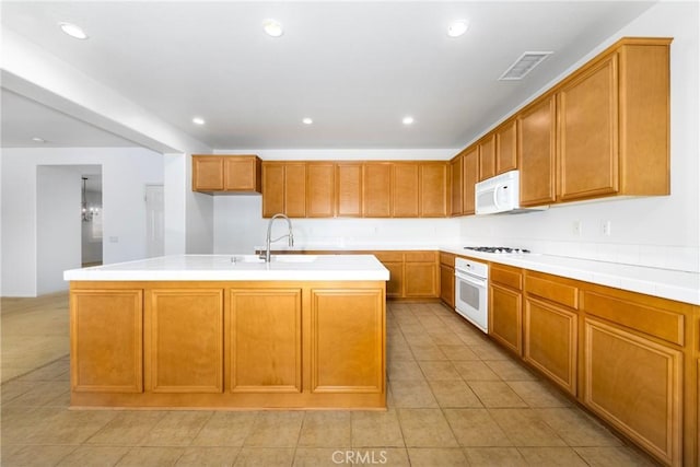 kitchen with white appliances, a sink, light tile patterned floors, light countertops, and recessed lighting
