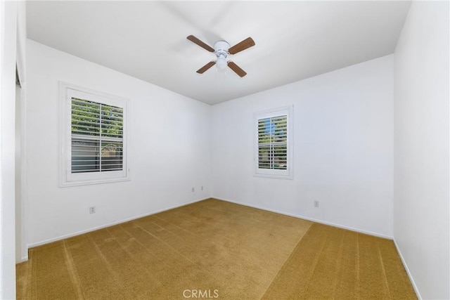 carpeted spare room featuring ceiling fan and baseboards