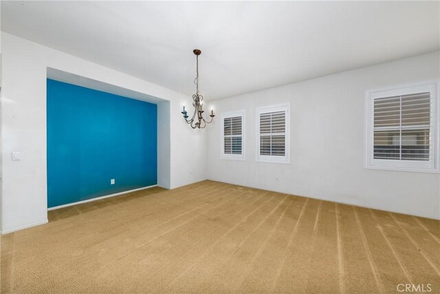 carpeted spare room featuring a chandelier