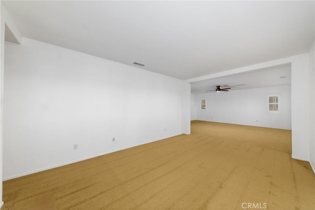 empty room featuring light carpet, a ceiling fan, and baseboards