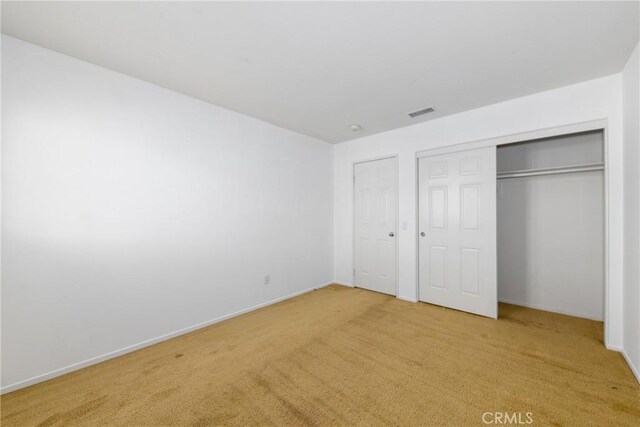 unfurnished bedroom featuring light carpet, baseboards, and a closet