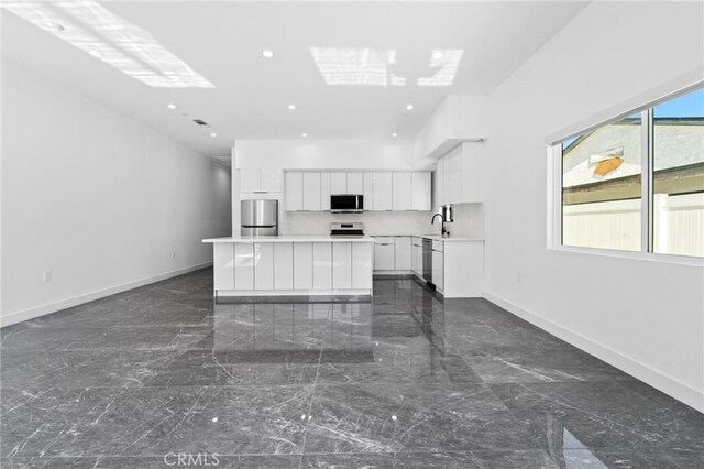 kitchen with appliances with stainless steel finishes, dark marble finish floors, modern cabinets, a center island, and recessed lighting