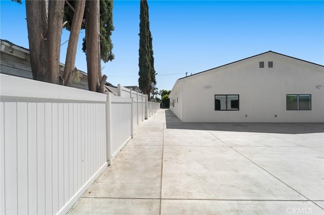 view of property exterior with fence, a patio area, and stucco siding