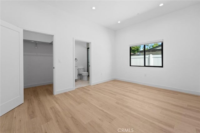 unfurnished bedroom with a walk in closet, light wood finished floors, recessed lighting, a closet, and baseboards