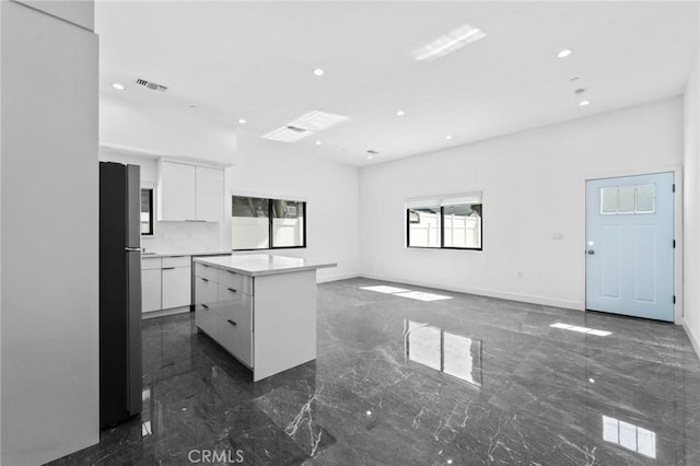 kitchen featuring modern cabinets, dark marble finish flooring, recessed lighting, freestanding refrigerator, and white cabinetry