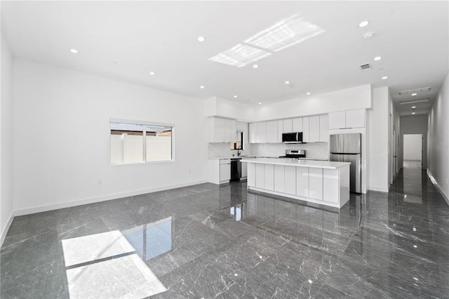 unfurnished living room with baseboards, recessed lighting, and dark marble finish flooring