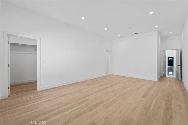 unfurnished bedroom with recessed lighting, light wood finished floors, a spacious closet, and baseboards
