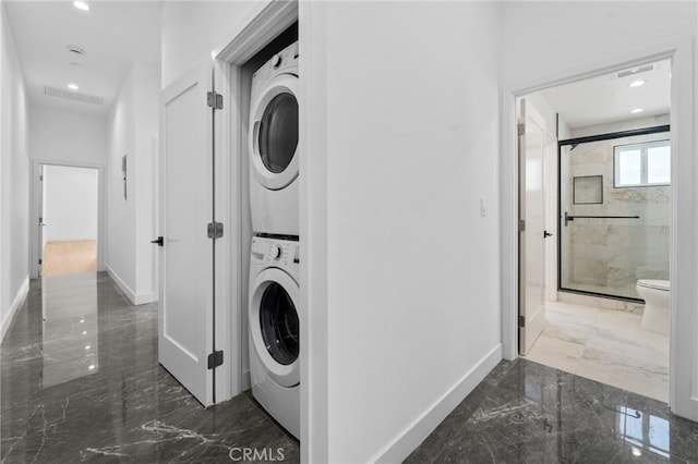 clothes washing area featuring stacked washing machine and dryer, marble tiled flooring, baseboards, and recessed lighting