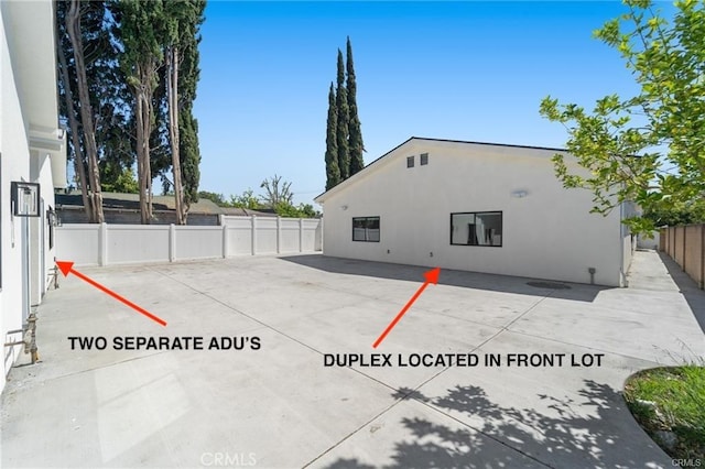 view of property exterior featuring fence, stucco siding, and a patio