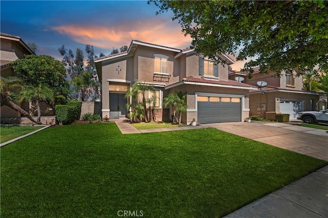 mediterranean / spanish-style house featuring stucco siding, a garage, driveway, a front yard, and a tiled roof