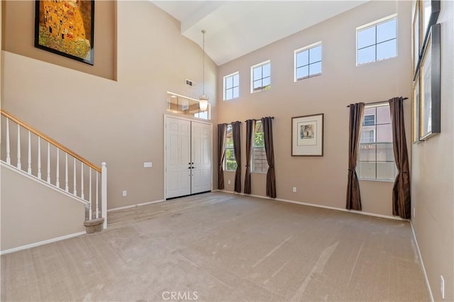 foyer entrance with carpet flooring, high vaulted ceiling, baseboards, and stairs