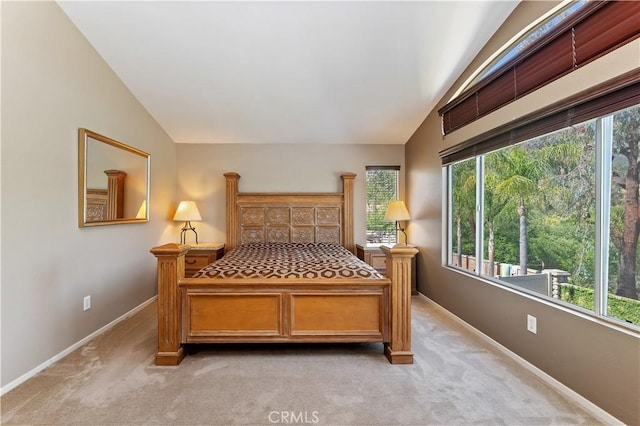 bedroom featuring lofted ceiling, multiple windows, and light colored carpet