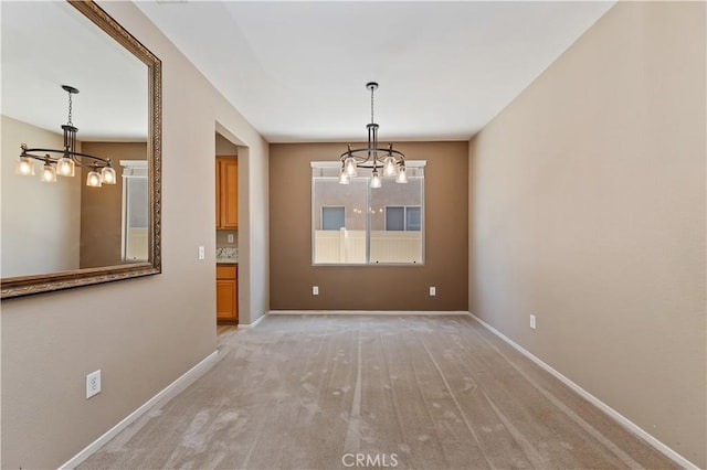 unfurnished dining area featuring a chandelier, baseboards, and light carpet