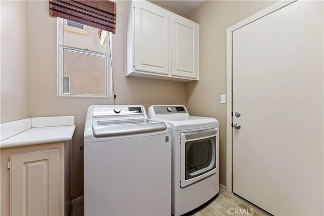 laundry area featuring cabinet space, washing machine and clothes dryer, and light wood finished floors