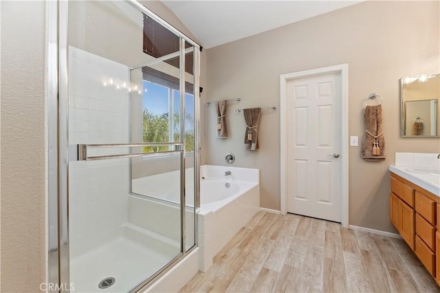 bathroom with a stall shower, wood finished floors, a bath, and vanity