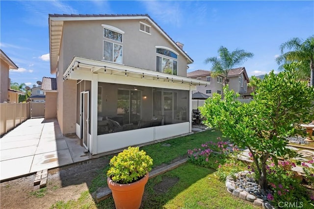 back of house with a sunroom, stucco siding, and a patio
