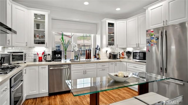 kitchen featuring stainless steel appliances, tasteful backsplash, white cabinetry, recessed lighting, and ornamental molding