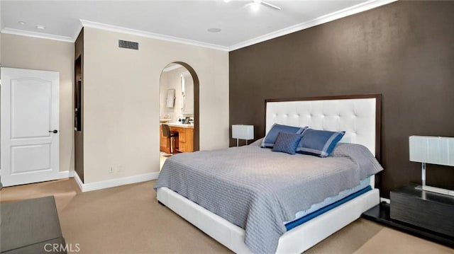 bedroom featuring arched walkways, crown molding, baseboards, carpet, and ensuite bath