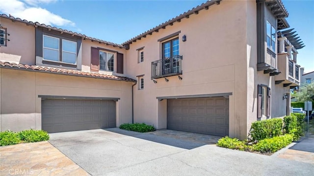 mediterranean / spanish house featuring a garage, stucco siding, a tiled roof, and driveway