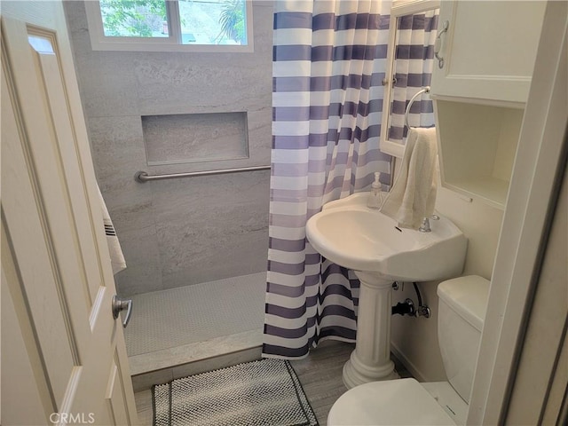 bathroom with toilet, a shower with shower curtain, and wood finished floors