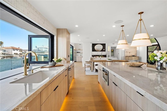 kitchen featuring a sink, light brown cabinets, modern cabinets, open floor plan, and recessed lighting