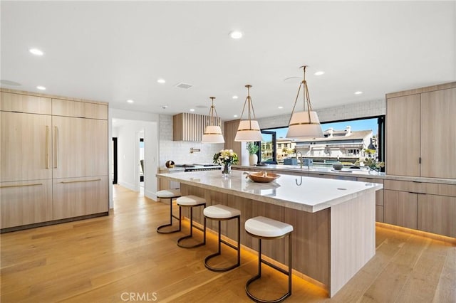 kitchen featuring modern cabinets, a large island, a breakfast bar area, light wood-style flooring, and recessed lighting