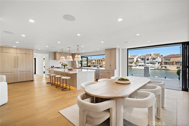 dining space with plenty of natural light, light wood-type flooring, recessed lighting, and a water view