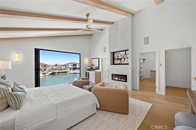 bedroom with beam ceiling, access to exterior, a large fireplace, high vaulted ceiling, and baseboards
