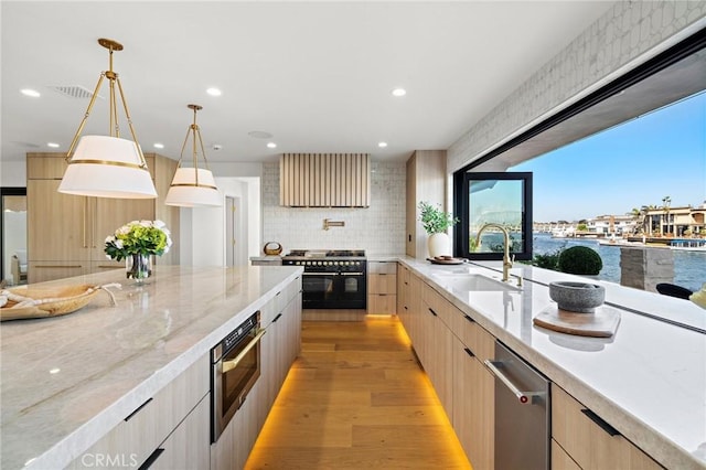 kitchen featuring modern cabinets, range with two ovens, light brown cabinetry, a sink, and recessed lighting