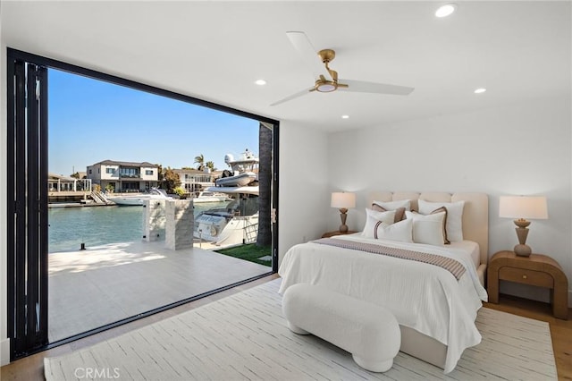 bedroom with floor to ceiling windows, access to exterior, a water view, wood finished floors, and recessed lighting