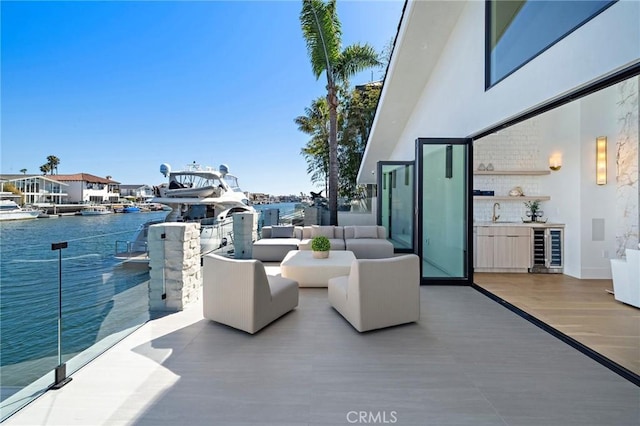 view of patio / terrace with wine cooler, a sink, an outdoor living space, and a water view