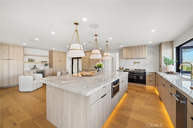 kitchen with modern cabinets, a sink, range with two ovens, backsplash, and stainless steel dishwasher