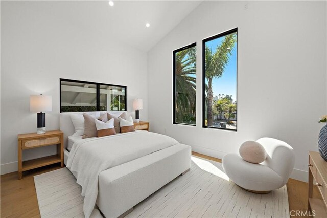 bedroom with recessed lighting, light wood-style floors, baseboards, and high vaulted ceiling