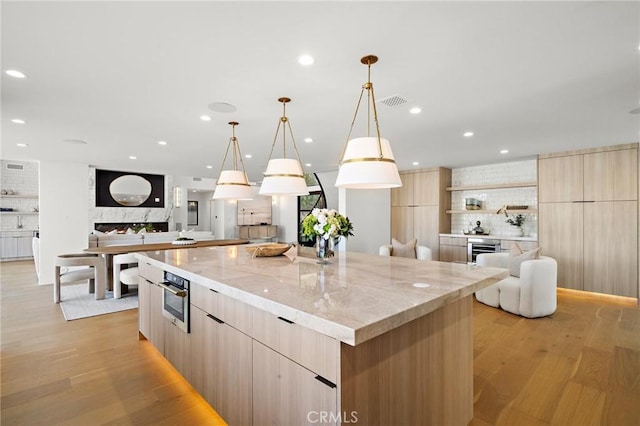 kitchen with modern cabinets, a spacious island, decorative backsplash, light brown cabinetry, and recessed lighting
