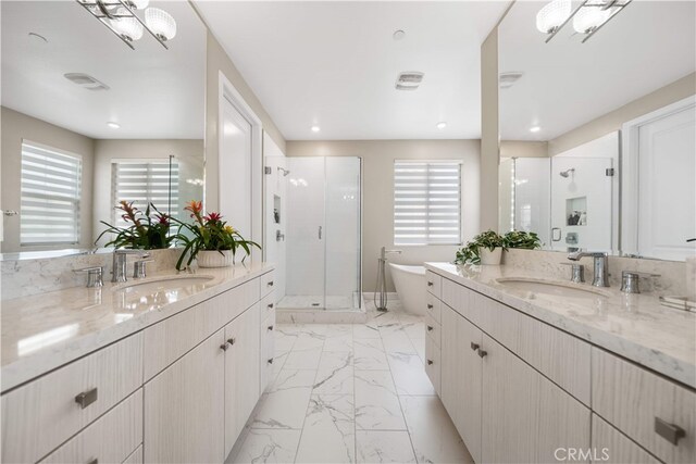 full bathroom with a shower stall, marble finish floors, plenty of natural light, and two vanities