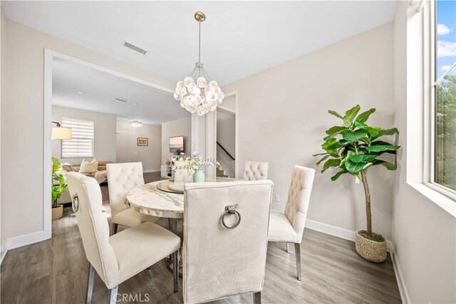 dining area with wood finished floors, baseboards, stairway, and a chandelier
