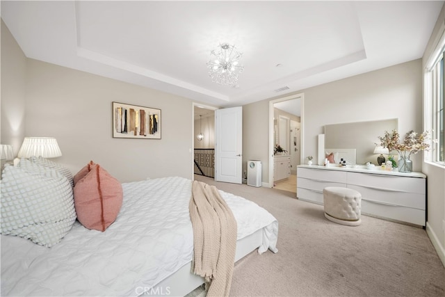 bedroom featuring a raised ceiling, light carpet, baseboards, and connected bathroom