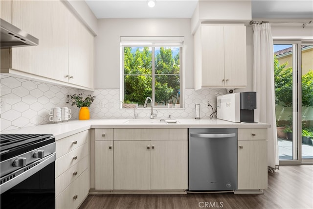 kitchen featuring appliances with stainless steel finishes, a sink, wall chimney exhaust hood, light countertops, and plenty of natural light