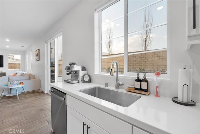 16708 Yarrow Ln, Fontana, CA 92336 - kitchen featuring a sink, dishwasher, white cabinetry, light wood-style floors, and light countertops
