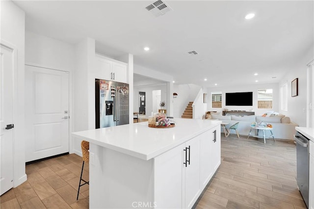 16708 Yarrow Ln, Fontana, CA 92336 - kitchen featuring stainless steel appliances, light wood-style floors, white cabinetry, recessed lighting, and a center island