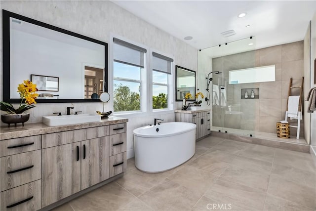 bathroom featuring a stall shower, two vanities, a soaking tub, tile patterned floors, and recessed lighting