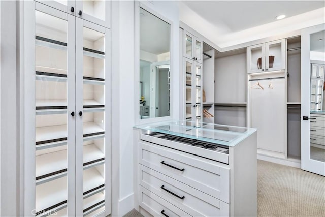 walk in closet with light carpet and french doors