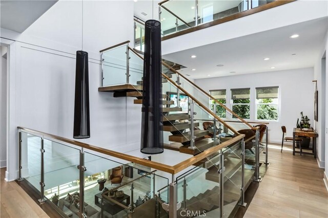 stairway featuring wood finished floors, recessed lighting, and baseboards