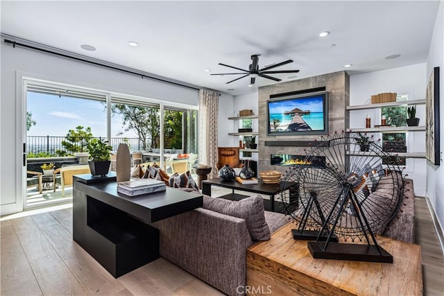 living room featuring wood finished floors, recessed lighting, a ceiling fan, and a tiled fireplace