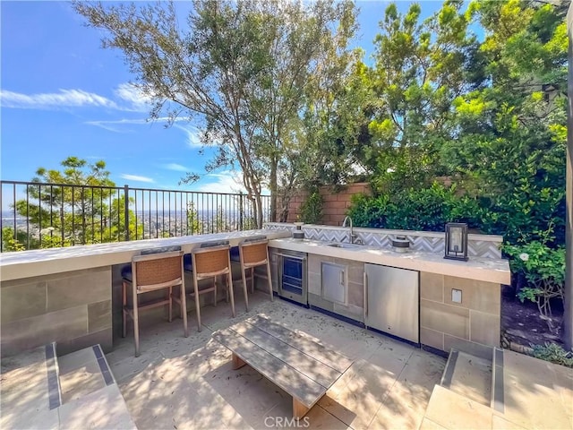 view of patio with exterior kitchen, fence, and wine cooler