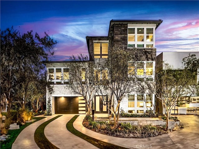 modern home featuring a garage, driveway, and stone siding
