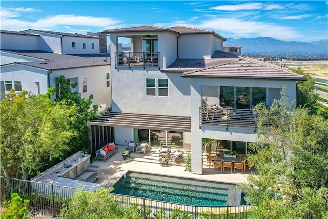 back of house featuring a balcony, an outdoor hangout area, stucco siding, a tile roof, and a mountain view