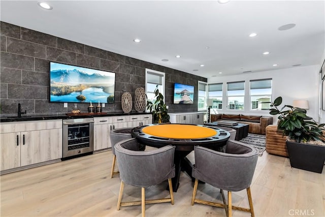 playroom featuring beverage cooler, bar with sink, recessed lighting, and light wood-style flooring