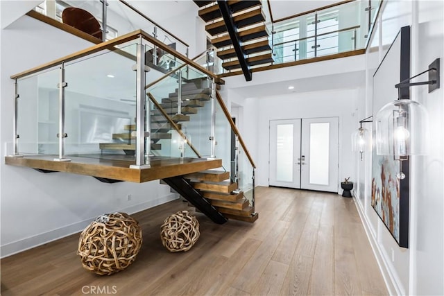 entryway featuring a towering ceiling, stairway, wood finished floors, and baseboards